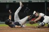 Atlanta Braves' Sam Hilliard, left, tumbles after being tagged out at home plate by Cleveland Guardians catcher David Fry, right, in the tenth inning of a baseball game Tuesday, July 4, 2023, in Cleveland. (AP Photo/Sue Ogrocki)