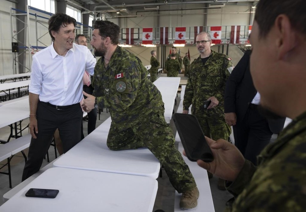 A Canadian soldier climbs on a table to speak with Prime Minister Justin Trudeau as he meets with Canadian troops stationed at the Adazi Military base, Monday, July 10, 2023 in Adazi, Latvia. Trudeau is in Vilnius, Lithuania, today for the NATO leaders' annual summit. THE CANADIAN PRESS/Adrian Wyld