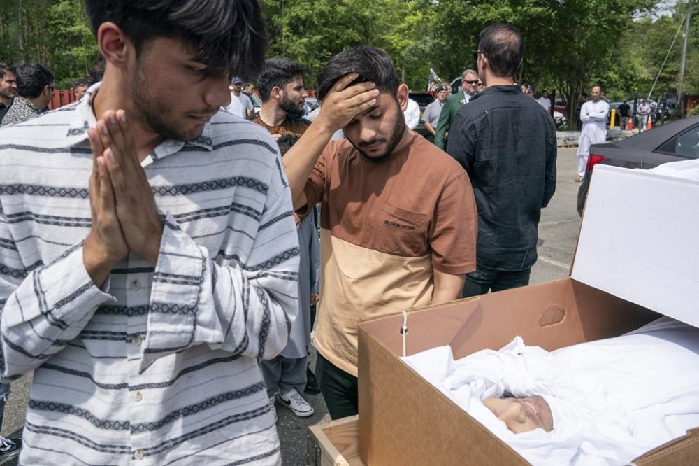 EDS NOTE: GRAPHIC CONTENT - Friends and family view the body of Nasrat Ahmad Yar, 31, during a funeral service at the All Muslim Association of America cemetery on Saturday, July 8, 2023 in Fredericksburg, Va. Ahmad Yar, an Afghan immigrant who worked as an interpreter for the U.S. military in Afghanistan, was shot and killed on Monday, July 3, while working as a ride-share driver in Washington. (AP Photo/Nathan Howard)