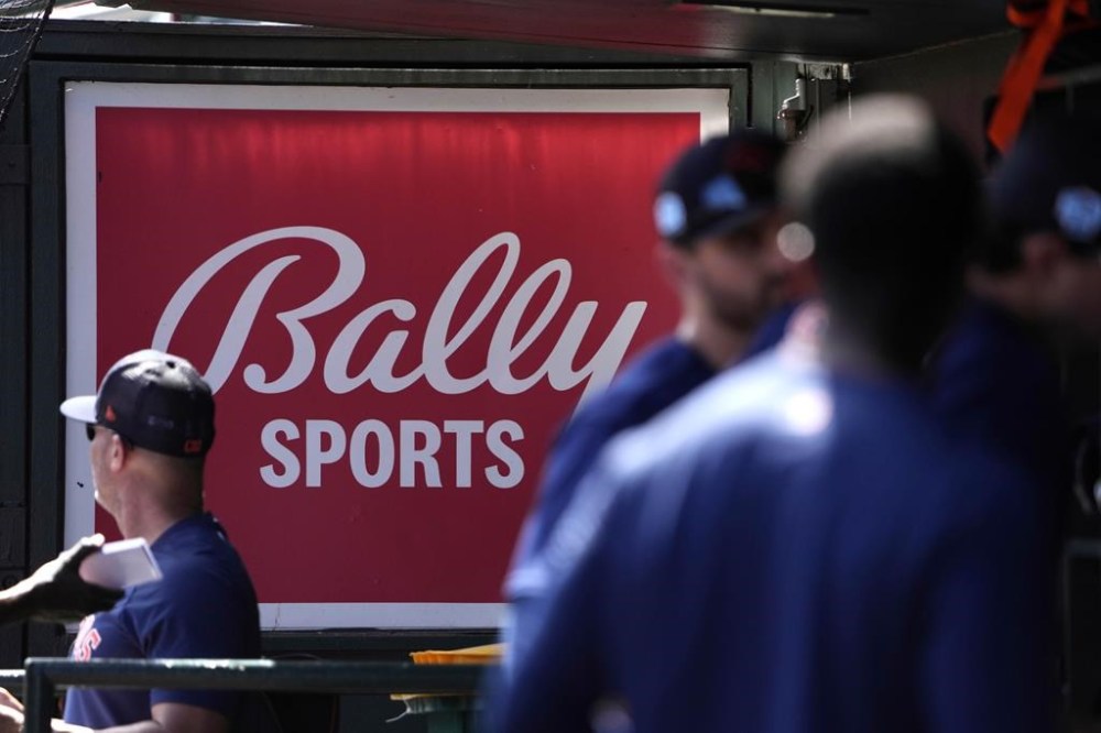 FILE -A Bally Sports sign hangs in a dugout before the start of a spring training baseball game between the St. Louis Cardinals and Houston Astros Thursday, March 2, 2023, in Jupiter, Fla. Major League Baseball says teams have collected 94% of the money they have been owed by Diamond Sports. The company owns 19 networks under the Bally Sports banner and has been in Chapter 11 bankruptcy proceedings in Texas since March. MLB took over rights to San Diego Padres telecasts on May 31 after a rights payment was missed.(AP Photo/Jeff Roberson, File)