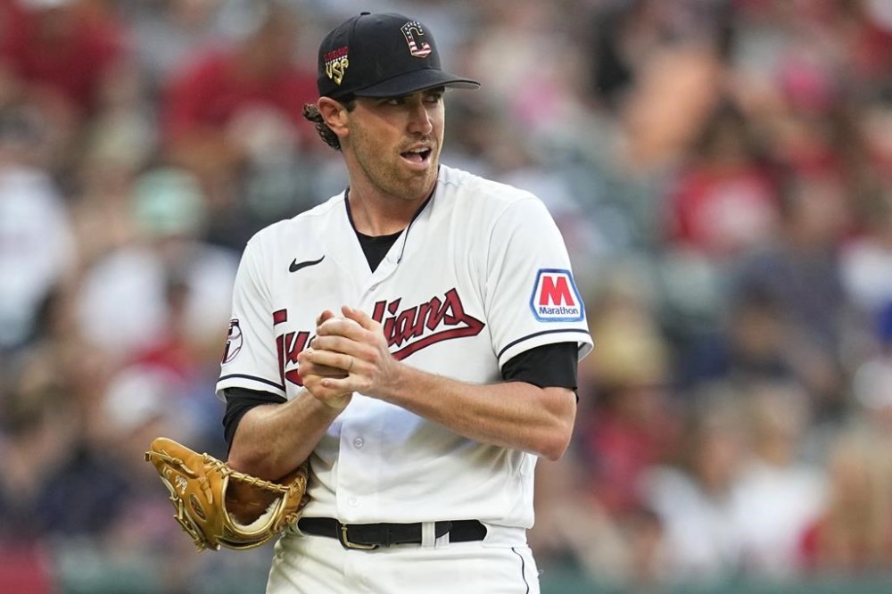 Cleveland Guardians starting pitcher Shane Bieber rubs up a new ball while Atlanta Braves' Ozzie Albies runs the bases on a home run during the fifth inning of a baseball game Tuesday, July 4, 2023, in Cleveland. (AP Photo/Sue Ogrocki)