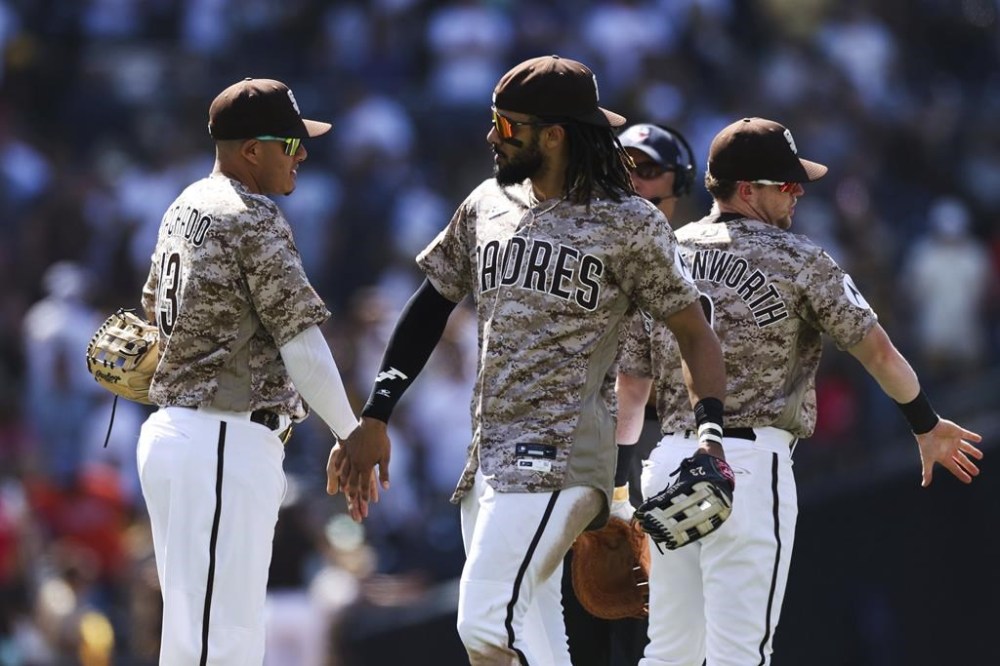 San Diego Padres' Fernando Tatis Jr., center, celebrates with Manny Machado, left, after they defeated the New York Mets in a baseball game Sunday, July 9, 2023, in San Diego. (AP Photo/Derrick Tuskan)
