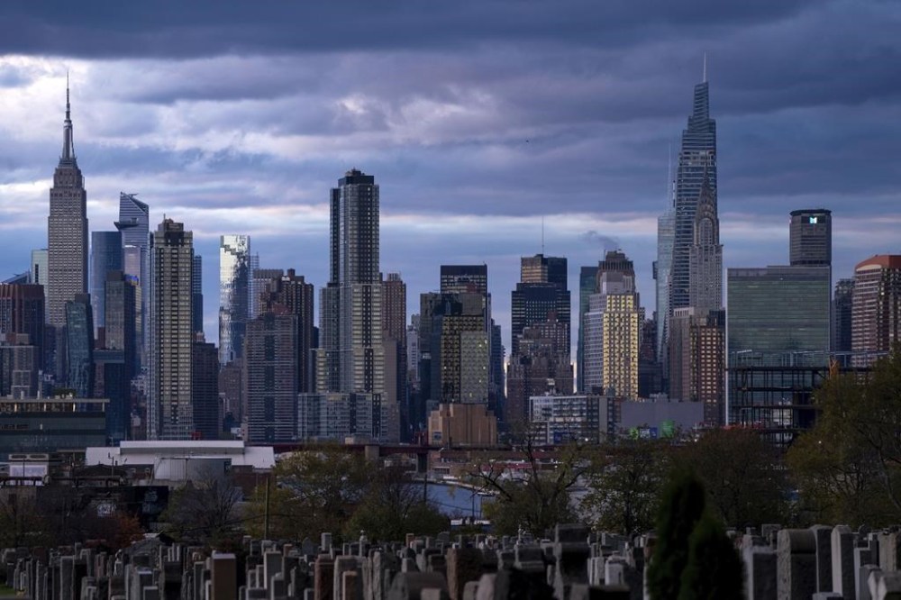 FILE - The sun sets behind the New York skyline, Sunday, Nov. 13, 2022, as seen from Calvary Cemetery. Two of the most populous states and two of the largest cities in the U.S. filed requests for corrections to their 2020 census figures at the end of last month. New York City officials believe 1,300 residents were overlooked. The head count may have missed an 800-bed jail and omitted or undercounted students living in dorms at Hunter College, Pace University and Wagner College, officials in the city's planning department said in a letter to the Census Bureau. (AP Photo/Julia Nikhinson, File)