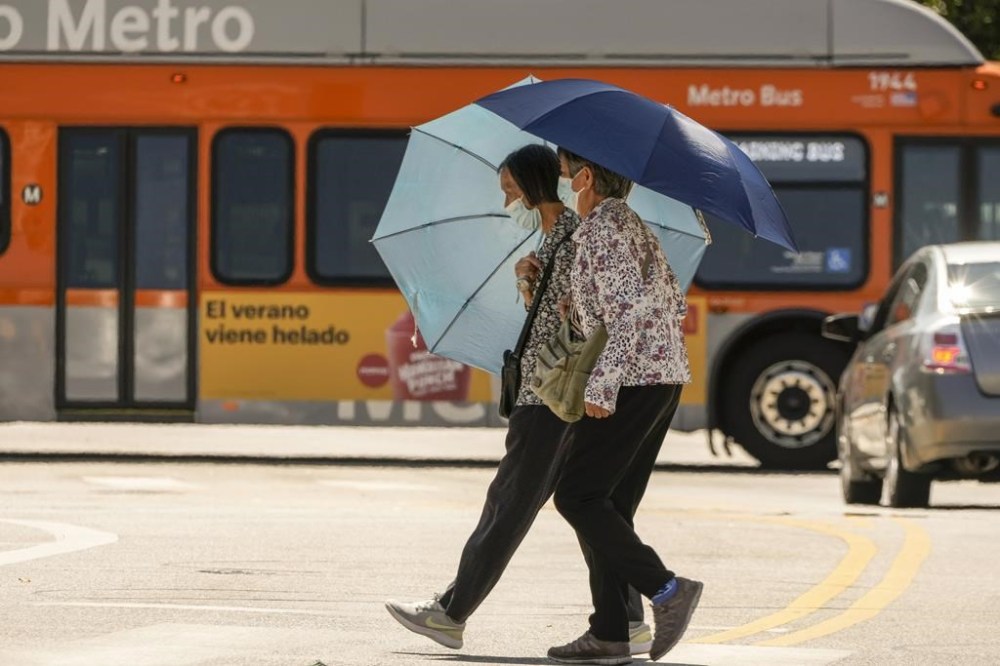 People wear face masks during excessive heat in the Chinatown district of Los Angeles, Thursday, July 13, 2023. After a historically wet winter and a cloudy spring, California's summer was in full swing Thursday as a heat wave that's been scorching much of the U.S. Southwest brings triple digit temperatures and an increased risk of wildfires. (AP Photo/Damian Dovarganes)