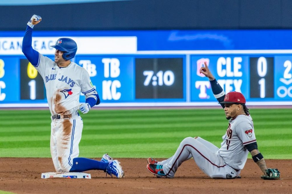 Toronto Blue Jays' George Springer (4) celebrates a double against Arizona Diamondbacks second baseman Ketel Marte (4) during fifth inning MLB baseball action in Toronto on Saturday, July 15, 2023. THE CANADIAN PRESS/Mathew Tsang