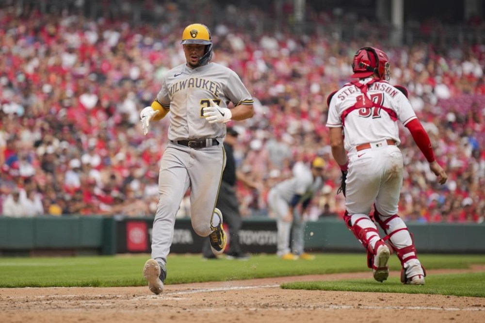 Milwaukee Brewers' Willy Adames, left, scores on a sacrifice fly by Owen Miller during the eighth inning of a baseball game against the Cincinnati Reds in Cincinnati, Sunday, July 16, 2023. (AP Photo/Aaron Doster)