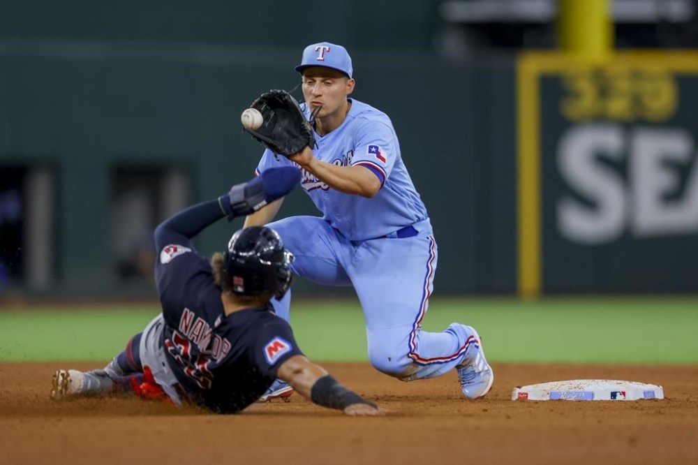 Texas Rangers' Corey Seager, right, completes a double play by tagging Cleveland Guardians' Josh Naylor, left, to end the fifth inning of a baseball game, Sunday, July 16, 2023, in Arlington, Texas. (AP Photo/Gareth Patterson)