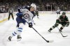 Winnipeg Jets center Morgan Barron, left, skates with the puck alongside Minnesota Wild defenseman Jon Merrill during the second period of an NHL hockey game in St. Paul, Minn., on April 11, 2023. THE CANADIAN PRESS/AP, Abbie Parr