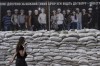 A woman walks past stacks of sandbags in front of a building in Kyiv, Ukraine, Monday, July 17, 2023. (AP Photo/Jae C. Hong)