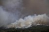 Smoke from a wildfire burns near houses in Pournari village near Athens, on Tuesday, July 18, 2023. In Greece, where a second heatwave is expected to hit Thursday, three large wildfires burned outside Athens for a second day. Thousands of people evacuated from coastal areas south of the capital returned to their homes Tuesday when a fire finally receded after they spent the night on beaches, hotels and public facilities. (AP Photo/Thanassis Stavrakis)