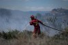 A firefighter directs water on a grass fire burning on an acreage behind a residential property in Kamloops, B.C., Monday, June 5, 2023. Firefighters battling British Columbia's hundreds of wildfires have had more obstacles to deal with beyond the record-sized blazes. THE CANADIAN PRESS/Darryl Dyck