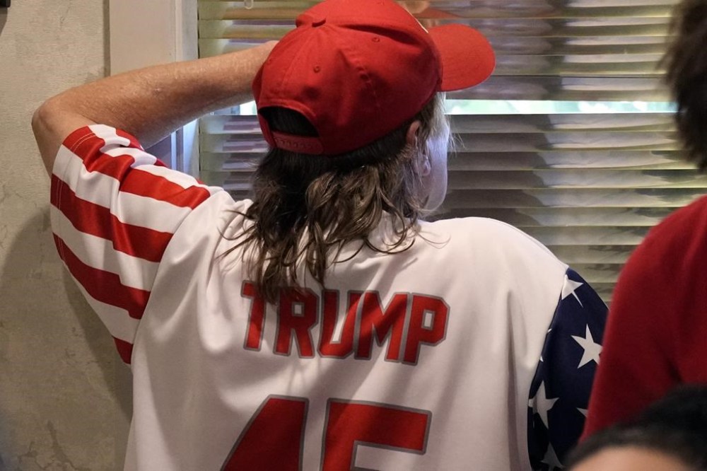 A supporter keeps watch for the arrival of former President Donald Trump at the Grimes Community Complex Park, Tuesday, July 18, 2023, in Des Moines, Iowa. (AP Photo/Charlie Neibergall)