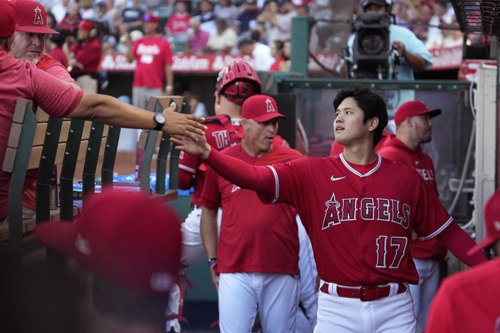 Los Angeles Angels' Shohei Ohtani, right, greets players in the dugout prior to a baseball game against the New York Yankees Tuesday, July 18, 2023, in Anaheim, Calif. (AP Photo/Mark J. Terrill)