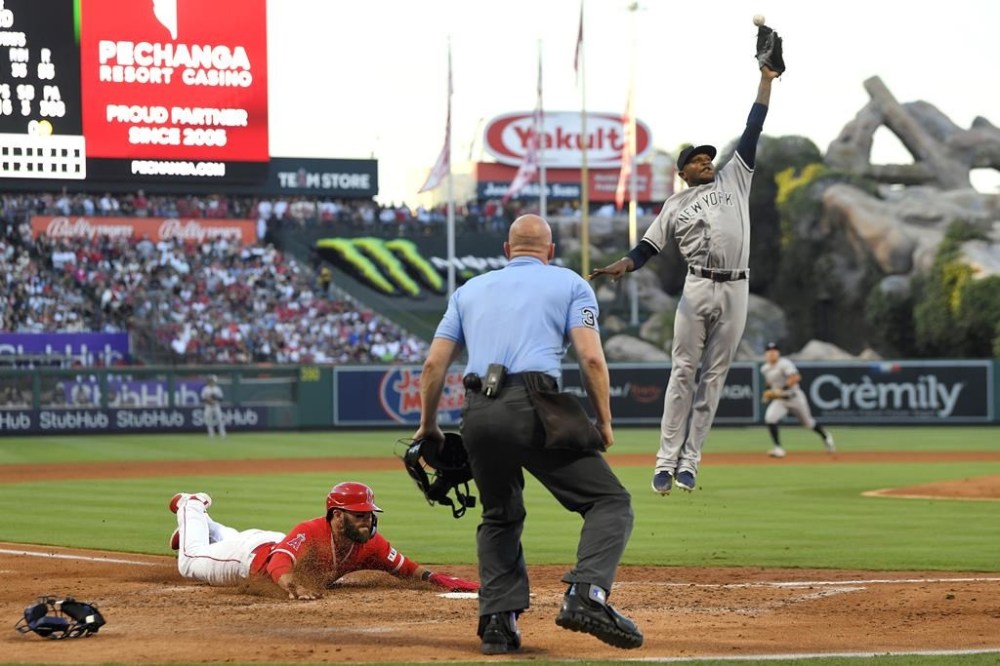 Los Angeles Angels' Michael Stefanic, left, scores on a wild pitch as New York Yankees starting pitcher Domingo German reaches for a high throw during the third inning of a baseball game Tuesday, July 18, 2023, in Anaheim, Calif. (AP Photo/Mark J. Terrill)