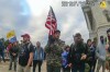 In this image from video provided by the Justice Department in the government's sentencing memo for Christopher Michael Alberts, right, yells at U.S. Capitol Police offices during the Jan. 6, 2021, riot at the U.S. Capitol. Alberts, a military veteran who stormed the U.S. Capitol with a loaded pistol, metal-plated body armor and a gas mask has been sentenced to seven years in prison. (Justice Department via AP)
