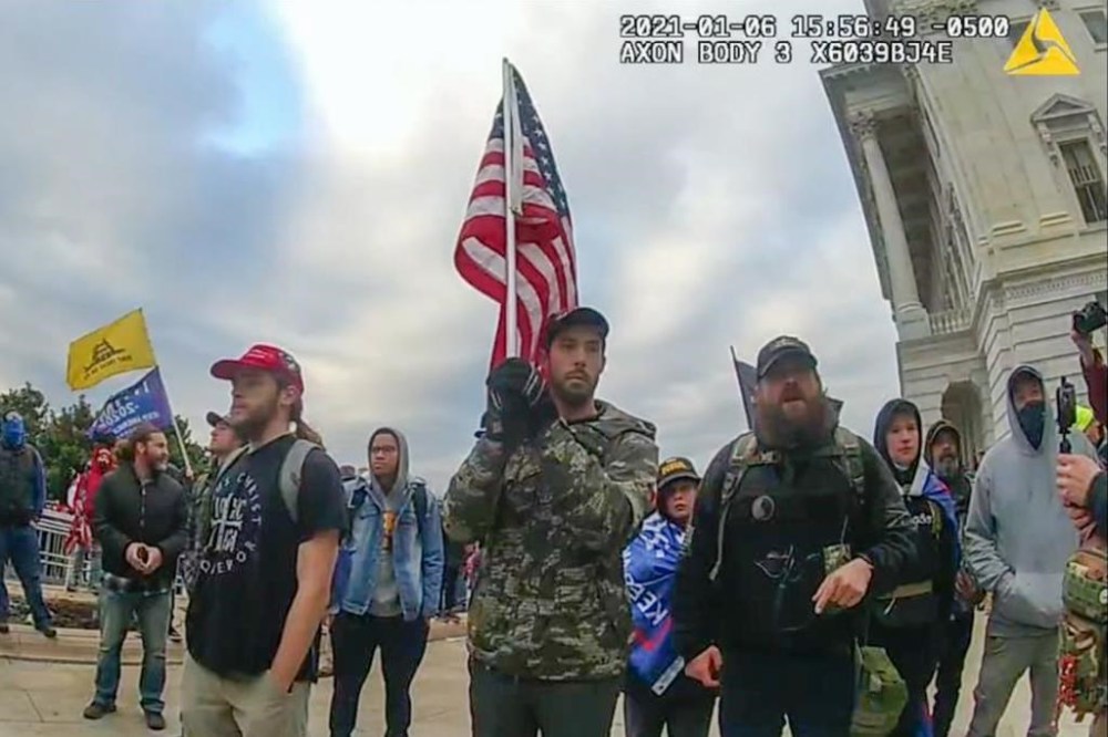 In this image from video provided by the Justice Department in the government's sentencing memo for Christopher Michael Alberts, right, yells at U.S. Capitol Police offices during the Jan. 6, 2021, riot at the U.S. Capitol. Alberts, a military veteran who stormed the U.S. Capitol with a loaded pistol, metal-plated body armor and a gas mask has been sentenced to seven years in prison. (Justice Department via AP)