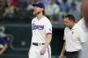 Texas Rangers starting pitcher Jon Gray looks up as head athletic trainer Matt Lucero, right, checks on him after Gray was hit by a single off the bat of Tampa Bay Rays' Yandy Diaz in the fifth inning of a baseball game, Wednesday, July 19, 2023, in Arlington, Texas. Gray left the game with an unknown leg injury. (AP Photo/Tony Gutierrez)