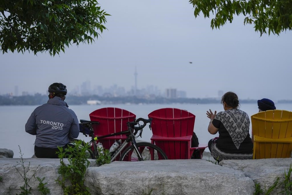 People sit along the waterfront at Humber Bay Park in Toronto on Wednesday, June 28, 2023. Toronto residents will be allowed to consume alcohol in a select number of parks across the city in the coming months after city council approved a time-limited pilot program. THE CANADIAN PRESS/Andrew Lahodynskyj