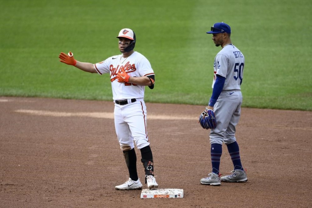 Baltimore Orioles' Ramon Urias, left, gestures as he stands on second after hitting a double during the third inning of a baseball game next to Los Angeles Dodgers second baseman Mookie Betts (50), Wednesday, July 19, 2023, in Baltimore. (AP Photo/Nick Wass)