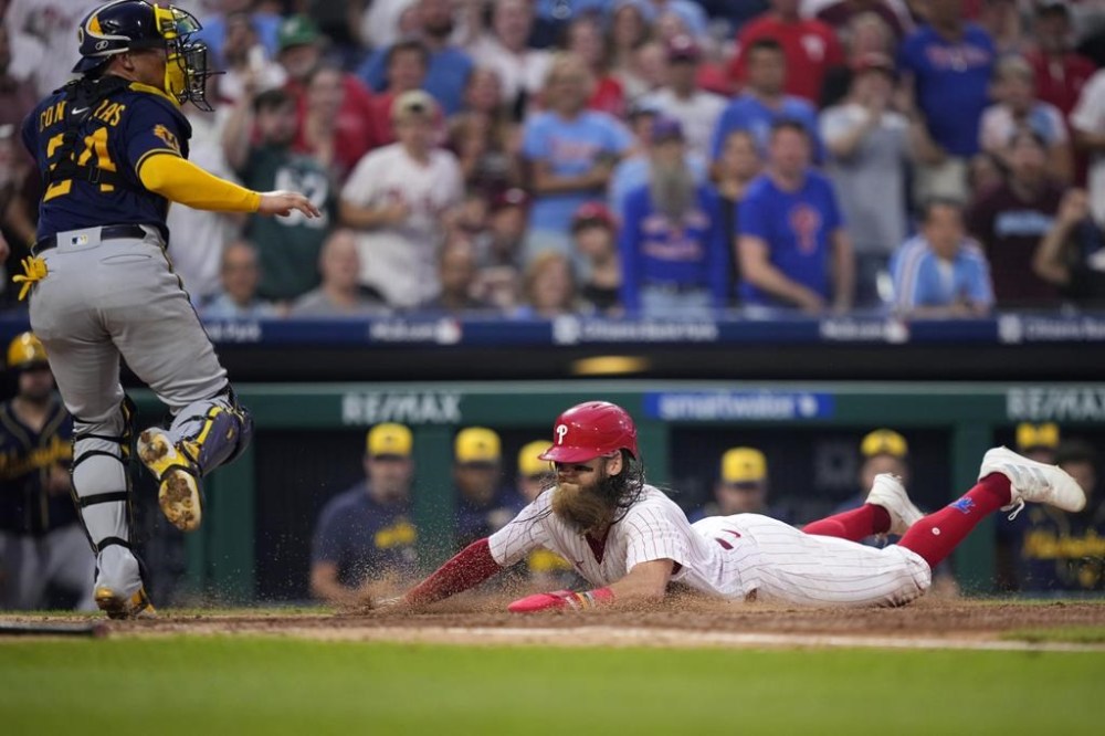 Philadelphia Phillies' Brandon Marsh, right, scores past Milwaukee Brewers catcher William Contreras on a two-run single by Kyle Schwarber during the fifth inning of a baseball game, Wednesday, July 19, 2023, in Philadelphia. (AP Photo/Matt Slocum)
