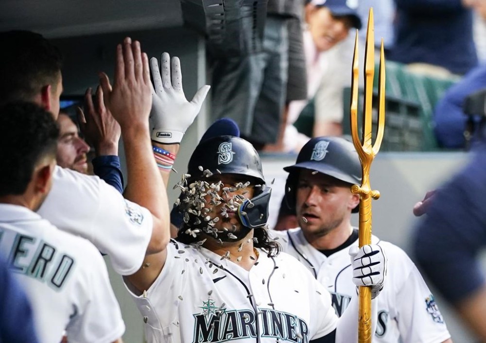 Seattle Mariners' Eugenio Suarez, center, has sunflower seeds tosses at his face in the dugout after his two-run home run against the Minnesota Twins during the seventh inning of a baseball game Wednesday, July 19, 2023, in Seattle. (AP Photo/Lindsey Wasson)