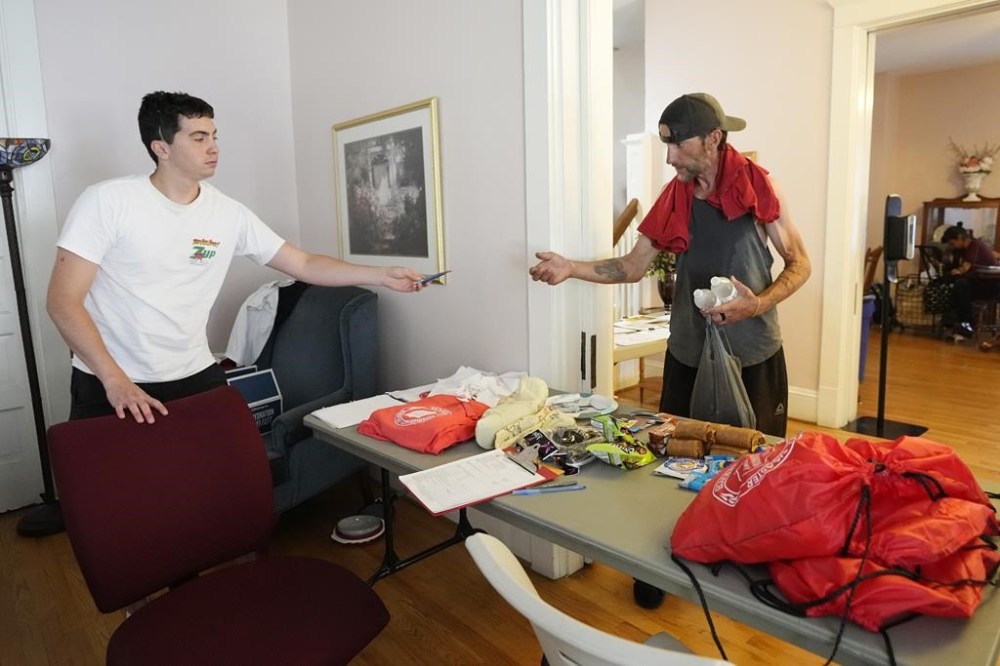 FILE - Manuel Luna, left, a volunteer at the Salvation Army, gives out items to a patron at a cooling station on July 19, 2023, in Phoenix. (AP Photo/Ross D. Franklin, File)