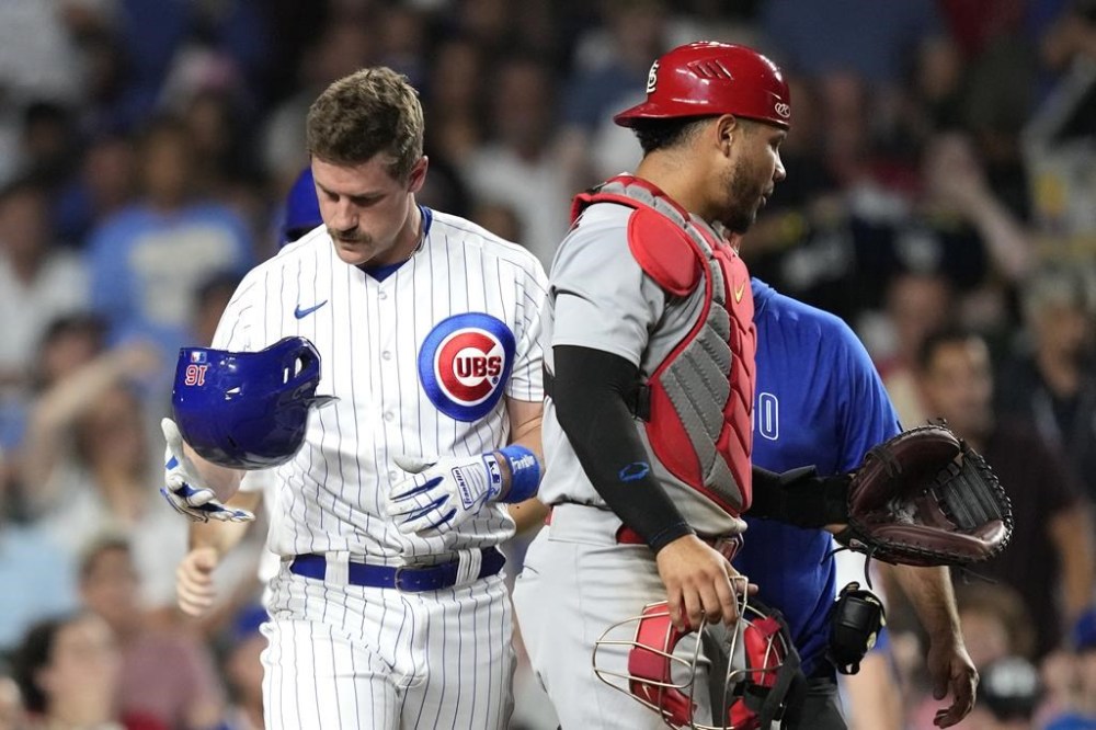 Chicago Cubs' Patrick Wisdom looks at his helmet after being struck on the helmet by a pitch from St. Louis Cardinals' Kyle Leahy, as catcher Willson Contreras stands nearby during the seventh inning of a baseball game Thursday, July 20, 2023, in Chicago. (AP Photo/Charles Rex Arbogast)