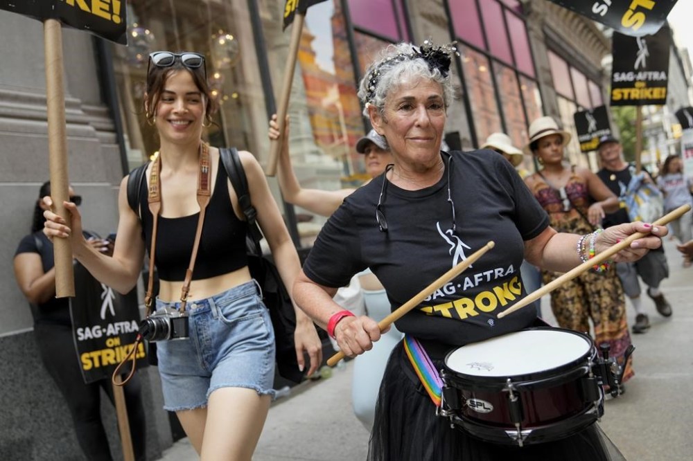 Striking writers and actors chant as they walk a picket line, Monday, July 17, 2023, in New York. Three years after the pandemic brought Hollywood to a standstill, the film and TV industry has again ground to a halt. This time, though, the industry is engaged in a bitter battle over the how streaming — after advancing rapidly during the pandemic — has upended the economics of entertainment. (AP Photo/John Minchillo)