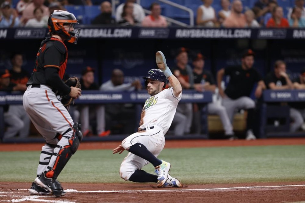 Tampa Bay Rays' Brandon Lowe, right, slides past Baltimore Orioles catcher Adley Rutschman to score during the second inning of a baseball game Friday, July 21, 2023, in St. Petersburg, Fla. (AP Photo/Scott Audette)