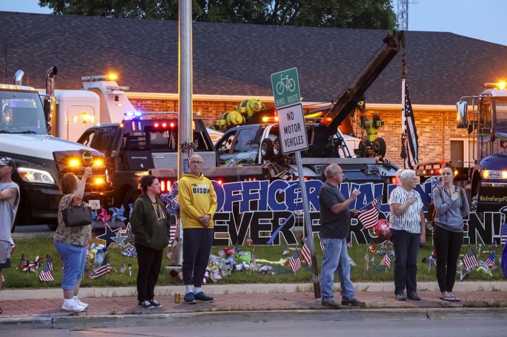 People watch an escort of the late Fargo Police Officer Jake Wallin pass in Fargo, N.D., Saturday, July 22, 2023. Wallin was killed July 14 when a man armed with 1,800 rounds of ammunition, multiple guns and explosives began firing on officers who were responding to a traffic crash. ( Amy Felegy/Minnesota Public Radio via AP)
