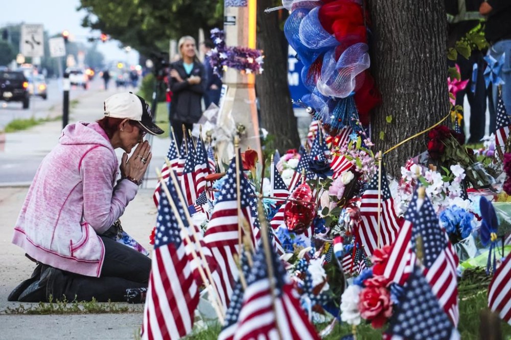 Julia L. Carlson-Vogel prays at the community memorial after an escort of the late Fargo Police Officer Jake Wallin passed by on the way to his funeral in Fargo, N.D., Saturday, July 22, 2023. Wallin was killed July 14 when a man armed with 1,800 rounds of ammunition, multiple guns and explosives began firing on officers who were responding to a traffic crash.( Amy Felegy/Minnesota Public Radio via AP)