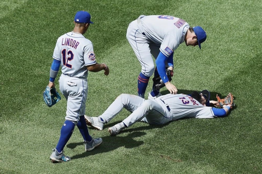 New York Mets' Brandon Nimmo (9) and Francisco Lindor (12) check on Luis Guillorme (13) after he was injured while fielding a single by Boston Red Sox's Rafael Devers during the sixth inning in the continuation of a suspended baseball game, Saturday, July 22, 2023, in Boston. The game was suspended the night before due to heavy rain. (AP Photo/Michael Dwyer)