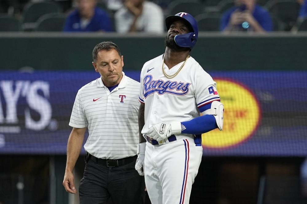 Texas Rangers head athletic trainer Matt Lucero, left, attends to Adolis Garcia, right, after Garcia was hit by a pitch in the eighth inning of a baseball game against the Tampa Bay Rays, Wednesday, July 19, 2023, in Arlington, Texas. Garcia left the game with an unknown left arm injury. (AP Photo/Tony Gutierrez)