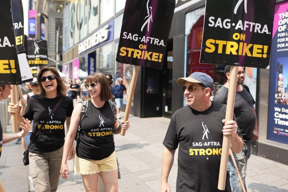 FILE - Actors Jennifer Van Dyck, left, and Jason Kravits, right, carry signs on a picket line outside Paramount in Times Square in New York on Monday, July 17, 2023. (Photo by Charles Sykes/Invision/AP, File)