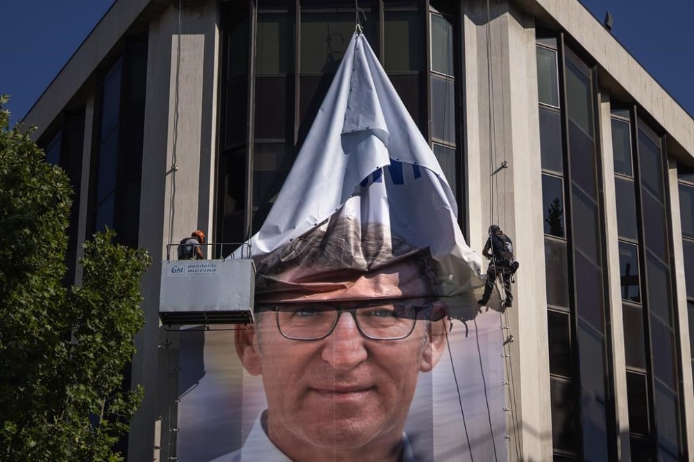 Workers remove an electoral poster showing Alberto Feijoo, leader of the mainstream conservative Popular Party, at the party headquarters in Madrid, Spain, Monday, July 24, 2023. Spaniards woke up Monday to find their country in political disarray after elections a day earlier left no party with a clear path to forming a government. (AP Photo/Emilio Morenatti)