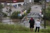 The cacophony caused by raging wildfires, searing heat and record-setting floods is caused by climate change, as world temperatures persistently increase, say experts. People stand on a hill surveying cars abandoned in floodwater in a mall parking lot following a major rain event in Halifax on Saturday, July 22, 2023. THE CANADIAN PRESS/Darren Calabrese