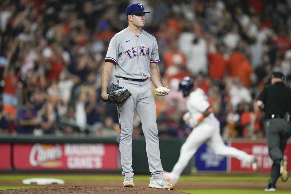 Texas Rangers relief pitcher Cody Bradford, left, applies rosin as Houston Astros' Martin Maldonado, back right, rounds the bases after hitting a solo home run during the seventh inning of a baseball game, Tuesday, July 25, 2023, in Houston. (AP Photo/Eric Christian Smith)