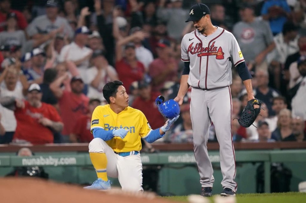 Boston Red Sox's Masataka Yoshida, left, is handed his helmet by Atlanta Braves starting pitcher Charlie Morton, right, after getting caught trying to advance to third, which was the third out of a triple play during the third inning of a baseball game at Fenway Park, Tuesday, July 25, 2023, in Boston. (AP Photo/Charles Krupa)