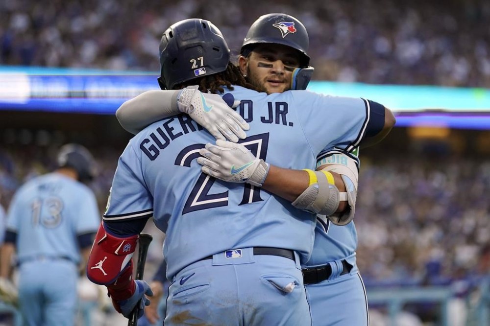 Toronto Blue Jays' Bo Bichette, right, is hugged by Vladimir Guerrero Jr. after Bichette's two-run home run against the Los Angeles Dodgers during the third inning of a baseball game Tuesday, July 25, 2023, in Los Angeles. (AP Photo/Marcio Jose Sanchez)