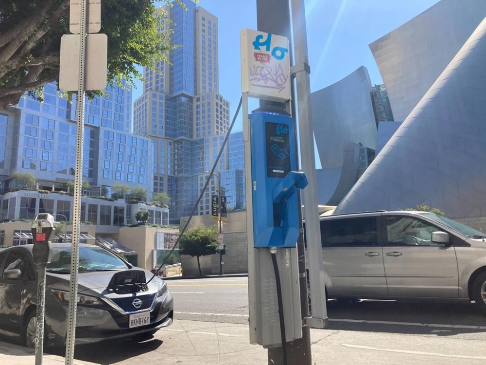FILE - An electric vehicle charges on a publicly accessible pole-mounted charger in Los Angeles on Oct. 4, 2022. The second-largest electric vehicle fast-charging network, Electrify America, with 800 direct-current fast-charging stations and more than 3,600 plugs nationwide, said Wednesday, July 26, 2023, it will work to add Tesla's connector to existing and future chargers by 2025. (AP Photo/Eugene Garcia, File)
