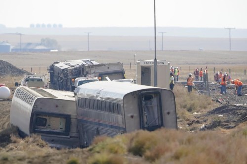 FILE - Workers stand near train tracks, Sept. 27, 2021, next to overturned cars from an Amtrak train that derailed near Joplin, Mont. On Thursday, July 27, 2023, federal investigators renewed their recommendation that railroads equip every locomotive with the kind of autonomous sensors that they believe could have caught the track flaws that caused the fatal 2021 Amtrak derailment in northern Montana. (AP Photo/Ted S. Warren, File)