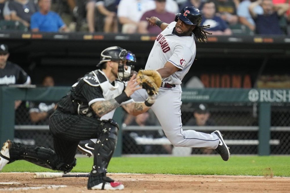 Cleveland Guardians' Josh Bell, right, slides by Chicago White Sox catcher Yasmani Grandal to score during the seventh inning of a baseball game Saturday, July 29, 2023, in Chicago. (AP Photo/Erin Hooley)