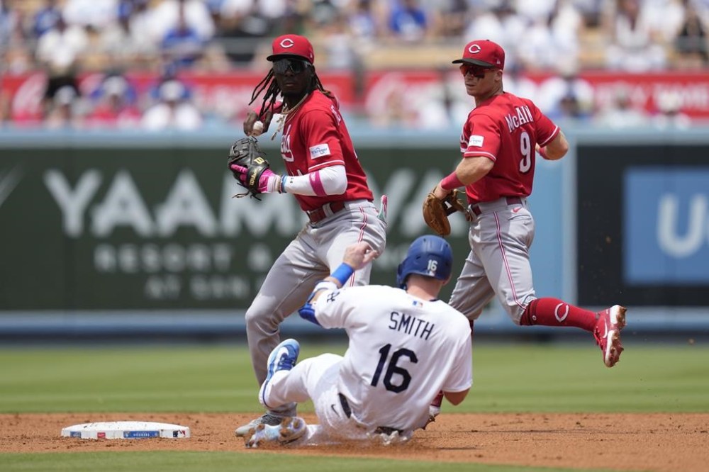 Cincinnati Reds shortstop Elly De La Cruz, left, throws to first over Los Angeles Dodgers' Will Smith (16) to turn a double play during the first inning of a baseball game in Los Angeles, Sunday, July 30, 2023. Max Muncy was out at first. (AP Photo/Ashley Landis)