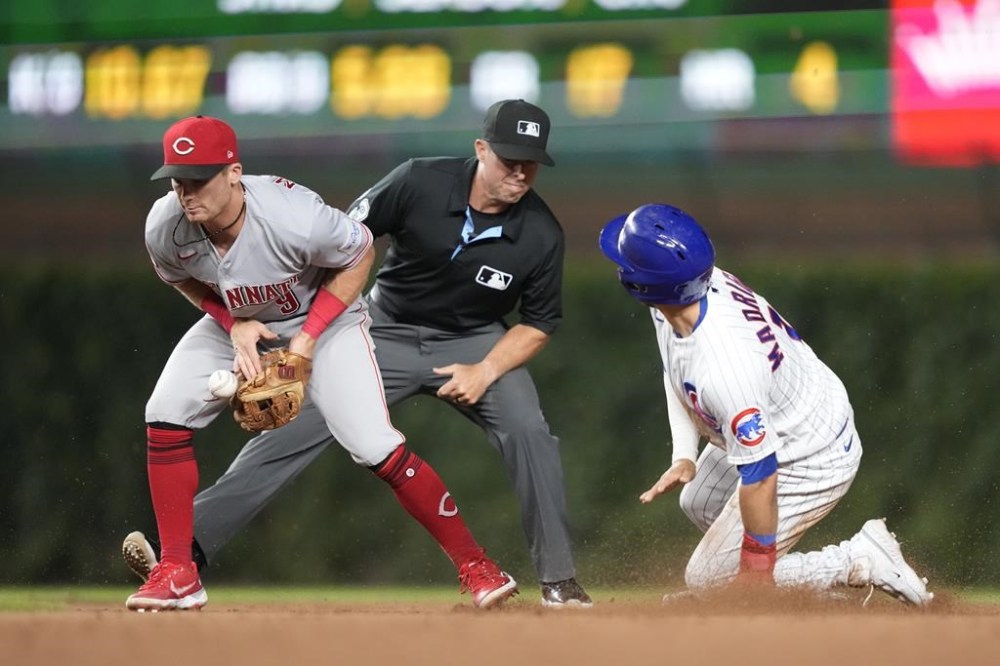 Chicago Cubs' Nick Madrigal, right, steals second as Cincinnati Reds shortstop Matt McLain is unable to field the throw from catcher Luke Maile, as second base umpire Tripp Gibson watches in the seventh inning of a baseball game Monday, July 31, 2023, in Chicago. (AP Photo/Charles Rex Arbogast)