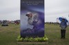 A spectator looks at a poster for the British Open 2024, featuring a picture of United States golfer Tiger Woods, as he walks around the commercial area at British Open Golf Championships at the Royal Liverpool Golf Club in Hoylake, England, Tuesday, July 18, 2023. The Open starts Thursday, July 20. (AP Photo/Kin Cheung)