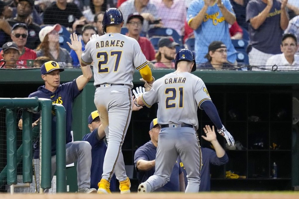 Milwaukee Brewers' Willy Adames and Mark Canha celebrate scoring on a single by Brice Turang during the fourth inning of a baseball game against the Washington Nationals at Nationals Park, Tuesday, Aug. 1, 2023, in Washington. (AP Photo/Alex Brandon)
