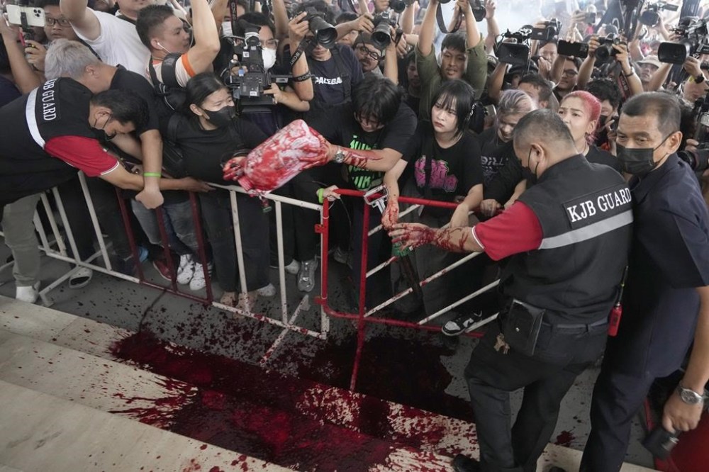 Supporters of the Move Forward Party splash water paints during a protest at Pheu Thai Party headquarters in Bangkok, Thailand, Wednesday, Aug. 2, 2023. Move Forward Party that won the most seats in May's general election will not be part of the coalition to form the next government amid strong opposition from conservative lawmakers over its proposed reform of laws surrounding the country's monarchy, its former coalition partner said Wednesday. (AP Photo/Sakchai Lalit)