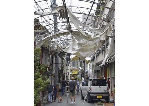 Workers try to restore the destruction caused by Typhoon Khanun, at a shopping district in Naha, Okinawa prefecture, southern Japan Thursday, Aug. 3, 2023. The typhoon that damaged homes and knocked out power on Okinawa and other Japanese islands this week was slowly moving west Thursday but is forecast to make a U-turn and dump even more rain on the archipelago. (Kyodo News via AP)