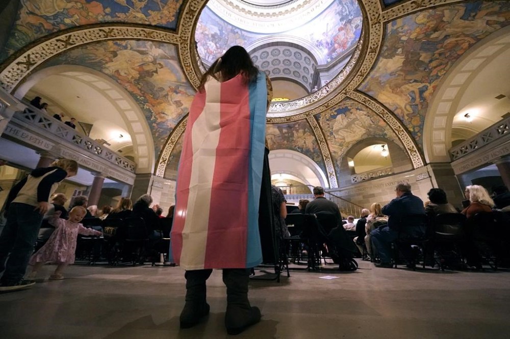 FILE - Glenda Starke wears a transgender flag as a counter protest during a rally in favor of a ban on gender-affirming health care legislation, March 20, 2023, at the Missouri Statehouse in Jefferson City, Mo. The American Academy of Pediatrics on Thursday, Aug. 3, 2023, reaffirmed its support for gender-affirming medical care for transgender children as the treatments face a growing push for bans and restrictions from Republican lawmakers. (AP Photo/Charlie Riedel, File)