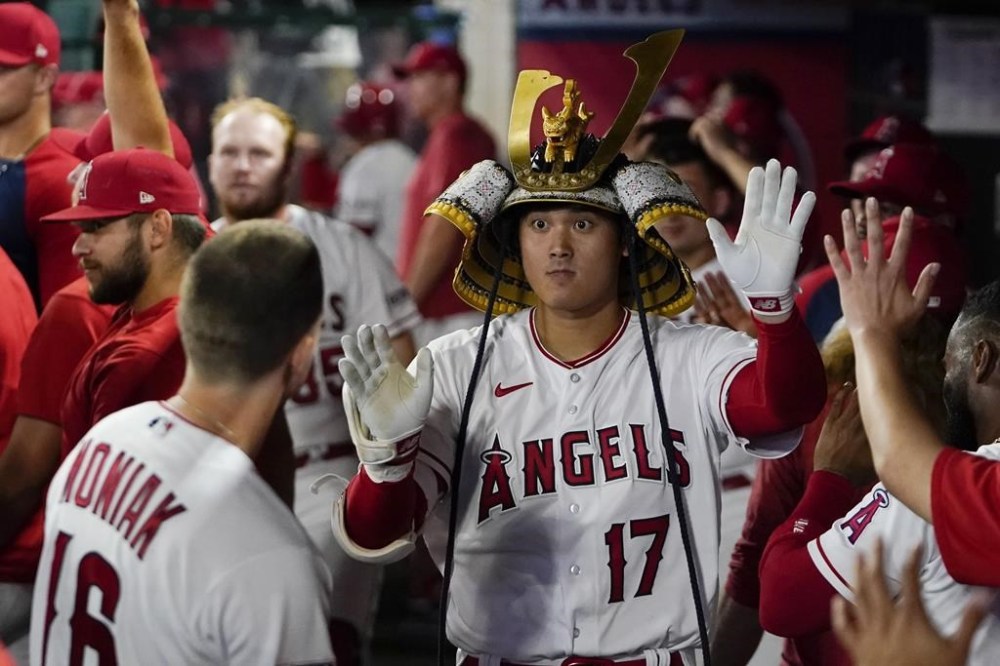 Los Angeles Angels' Shohei Ohtani celebrates in the dugout while wearing a hat after hitting a home run against the Seattle Mariners during the eighth inning of a baseball game Thursday, Aug. 3, 2023, in Anaheim, Calif. (AP Photo/Ryan Sun)